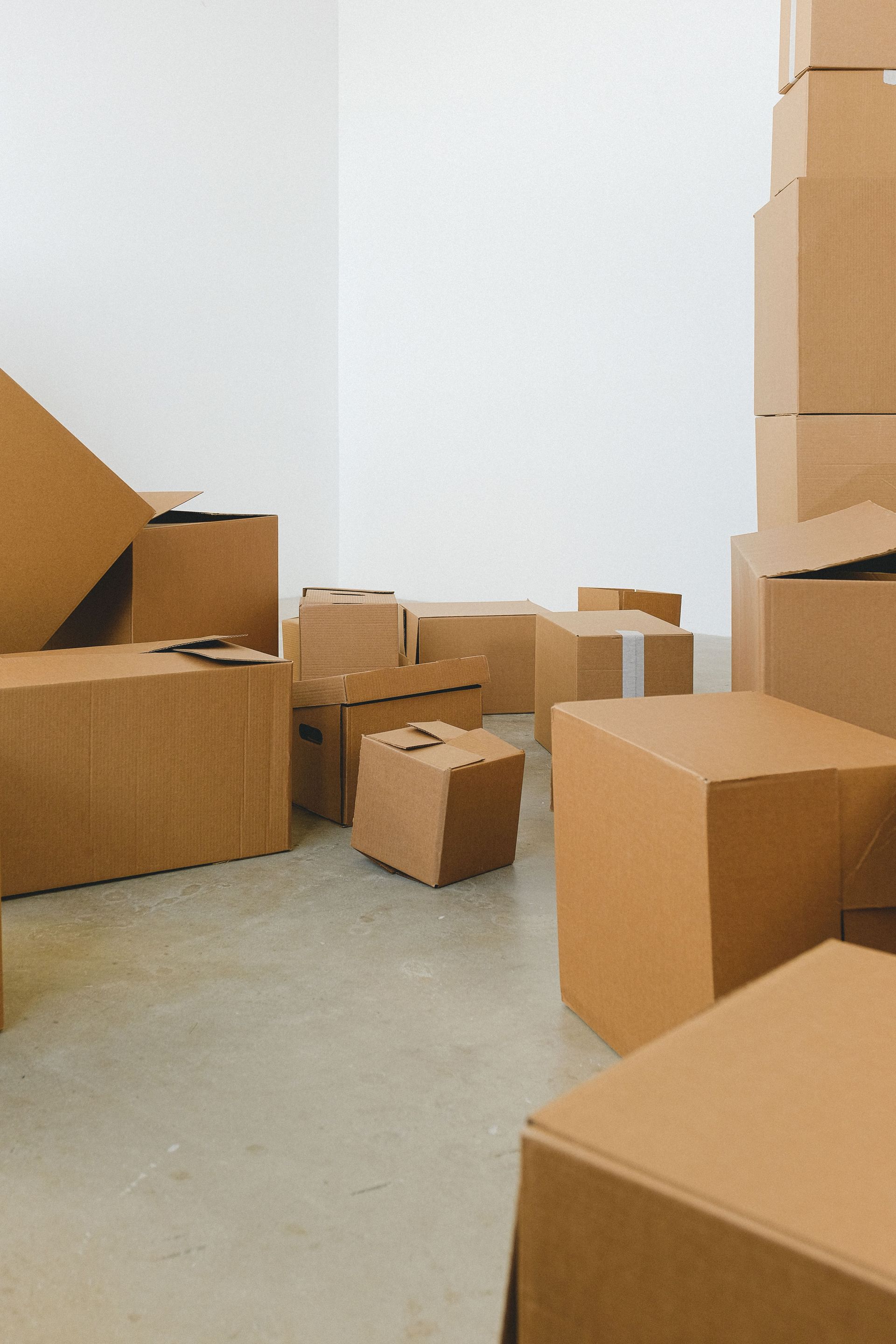 Heaps of different cardboard boxes on floor in rented house in daytime on white background